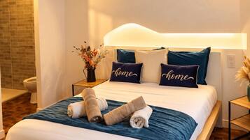 Une chambre moderne avec un grand lit, une table de chevet, une commode et une lampe fixée au mur.