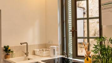 Una cocina moderna con estufa integrada, pileta y ventana con contraventanas.