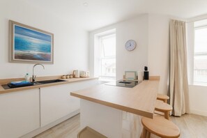 Une cuisine moderne avec un îlot central, un évier et une horloge au mur.