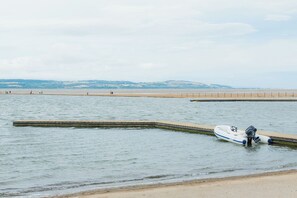 A calm body of water with a small motorboat docked at a concrete pier. - West Kirby Gem Walk to Marine Lake & beach (West Kirby)