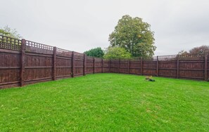 Ein Garten mit Zaun, Rasen und einem Baum.