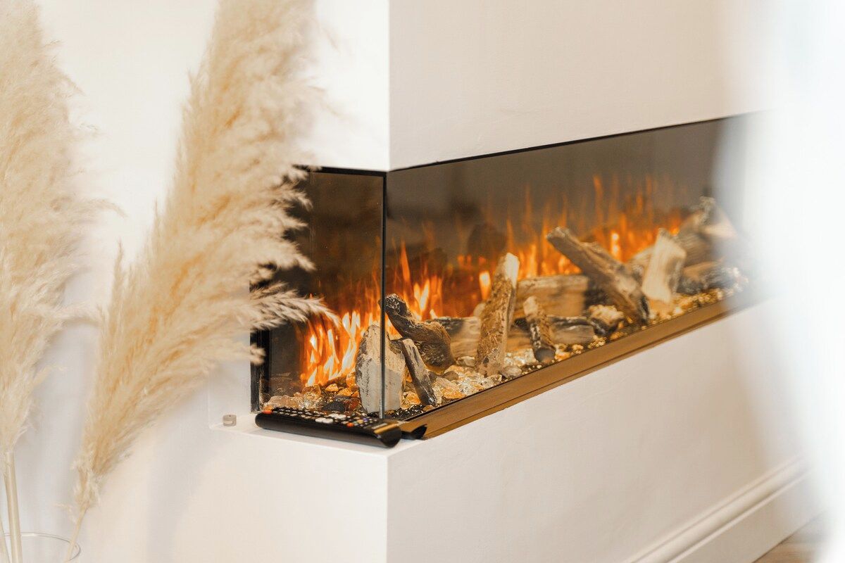 A wall-mounted fireplace with a visible fire, surrounded by decorative stones and logs.