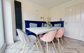 A dining area with a table, chairs, a bench, and a decorative sign. - 3-Bed Chester Home | Parking | Near Chester Zoo (Cheshire West and Chester)