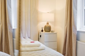 A hotel room with a bed, a bedside table with a lamp, and a window with curtains. - 3-Bed Chester Home | Parking | Near Chester Zoo (Cheshire West and Chester)