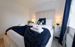 Ein Hotelzimmer mit einem Bett, zwei Nachttischen, einem Heizkörper und einem Fenster mit Vorhängen.