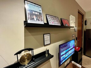 A wall with framed pictures, a television displaying a movie, and a sign indicating WiFi availability. - Japanese Studio I Hiranandani Estate I AC (Thane)