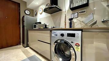 A compact kitchen with a built-in washer and dryer, a microwave, and a refrigerator.