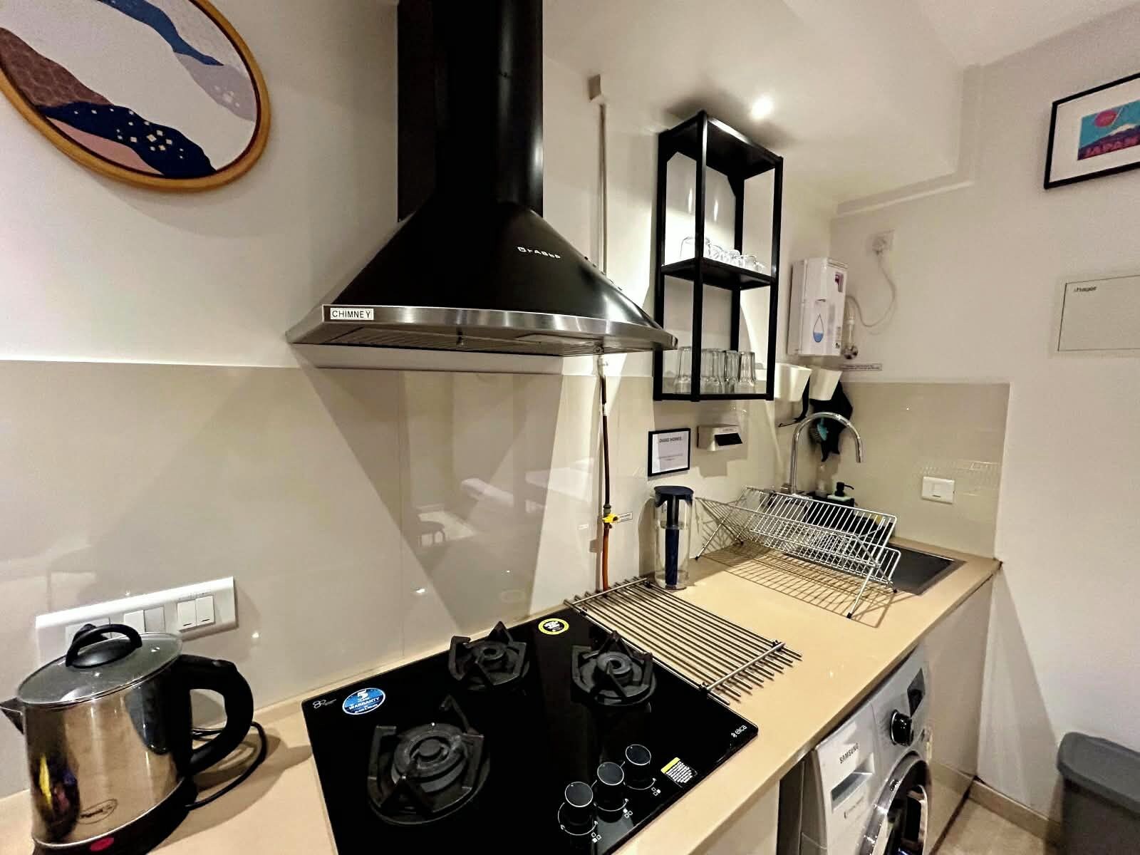 A compact kitchen with a stove, a kettle, a built-in oven, and a microwave.