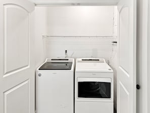 A laundry room with a front-loading washer and dryer, a sink, and a tiled backsplash. - Peaceful Lakefront Retreat on Watts Bar with Private Boat Ramp (Spring City)