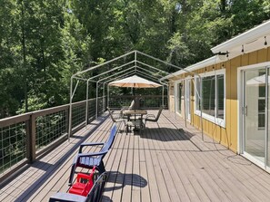 A covered outdoor deck with a table and chairs, surrounded by a wooden railing and glass doors. - Peaceful Lakefront Retreat on Watts Bar with Private Boat Ramp (Spring City)