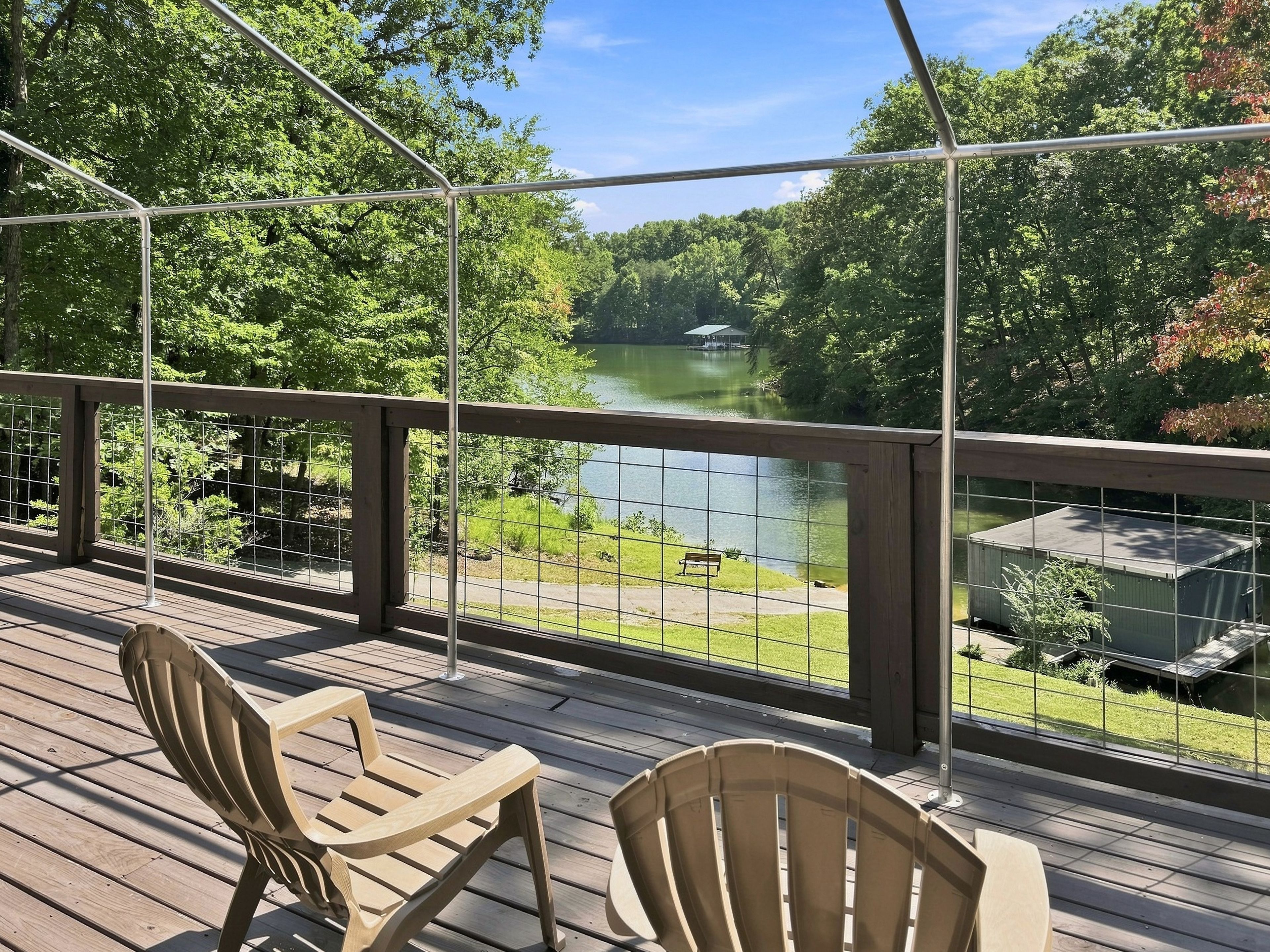 Une terrasse en bois avec deux chaises donnant sur un lac et une végétation luxuriante.