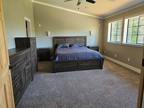 Ein Schlafzimmer mit Bett, Kommode, Nachttischen und einem Fenster.