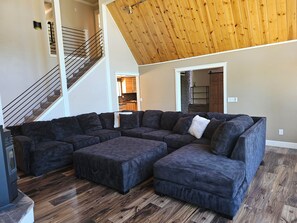 A large L-shaped sectional sofa in a spacious living area with a wooden floor and a high ceiling. - Spacious 4-bedroom house in Pioneer Ca with AC and Heat (Pioneer)