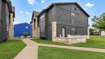 A residential building with a stone foundation, a gray exterior, and a blue accent wall.