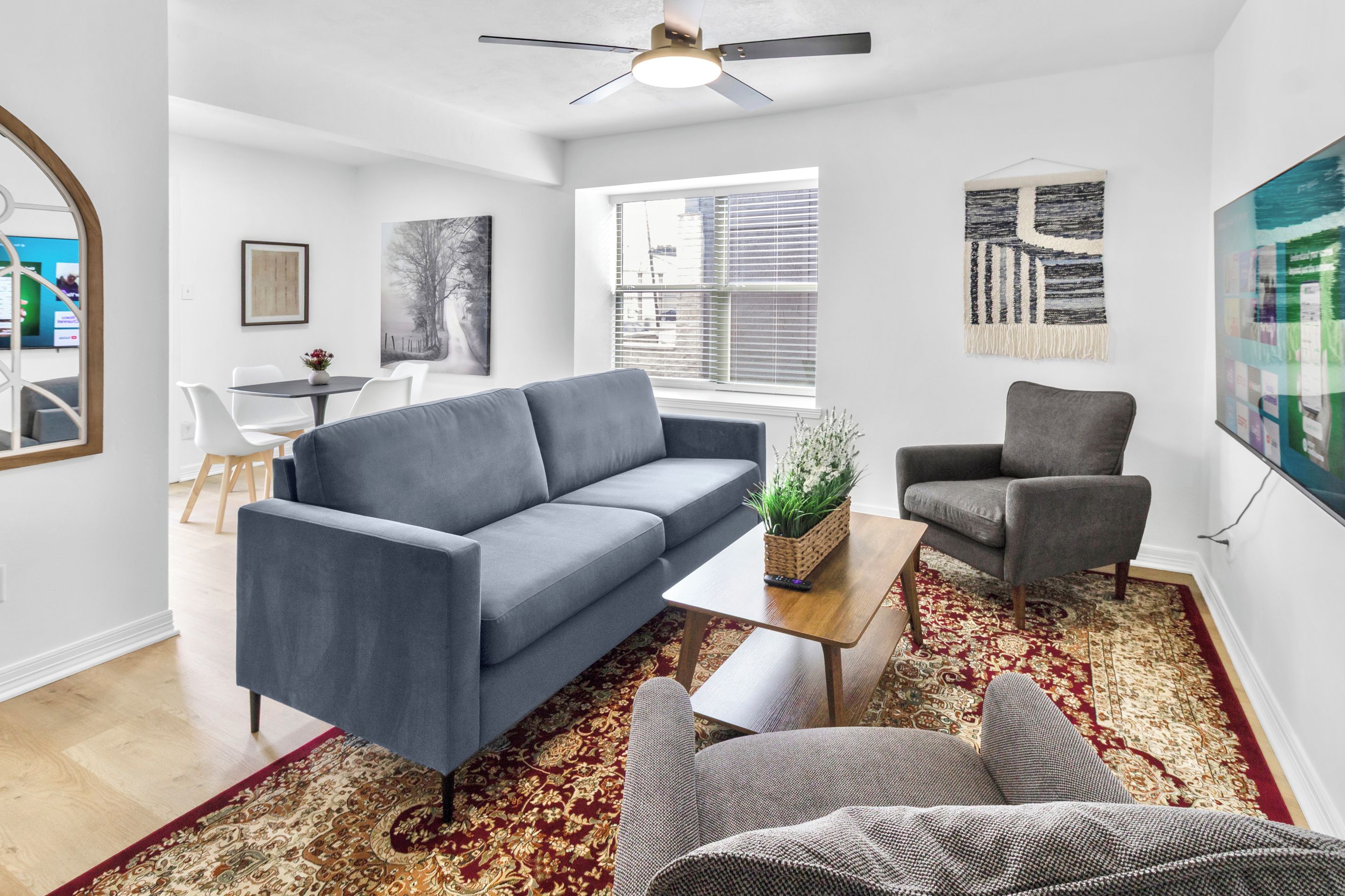 A living room with a grey sofa, a grey armchair, a coffee table, and a patterned rug.