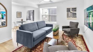 A living room with a grey sofa, a grey armchair, a coffee table, and a patterned rug.