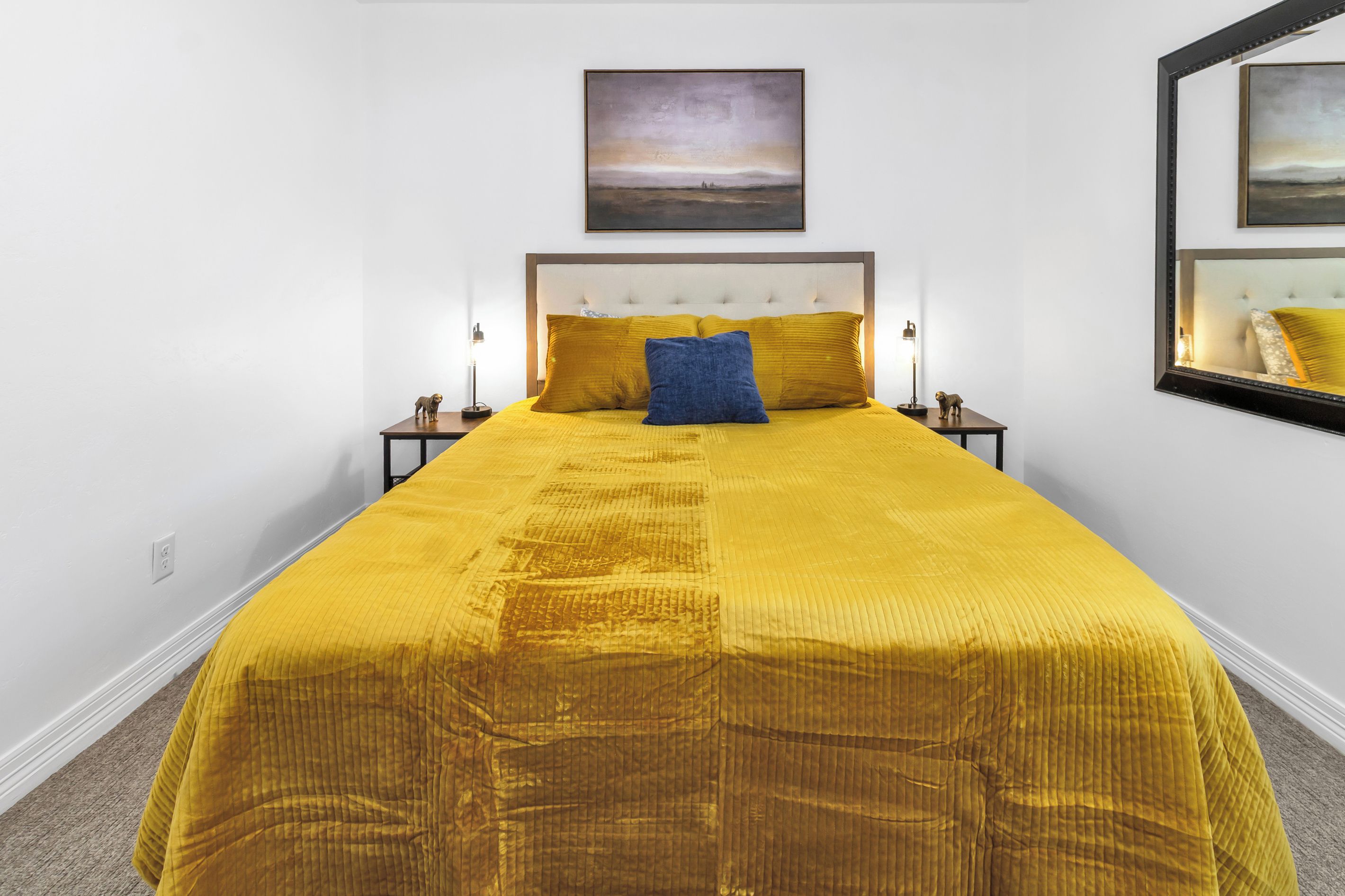 A bed with a headboard, two bedside lamps, and a single pillow.