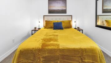 A bed with a headboard, two bedside lamps, and a single pillow.
