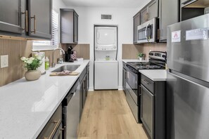 Une cuisine moderne équipée d’appareils électroménagers en acier inoxydable, d’un four encastré, d’un four à micro-ondes et d’un lave-vaisselle.