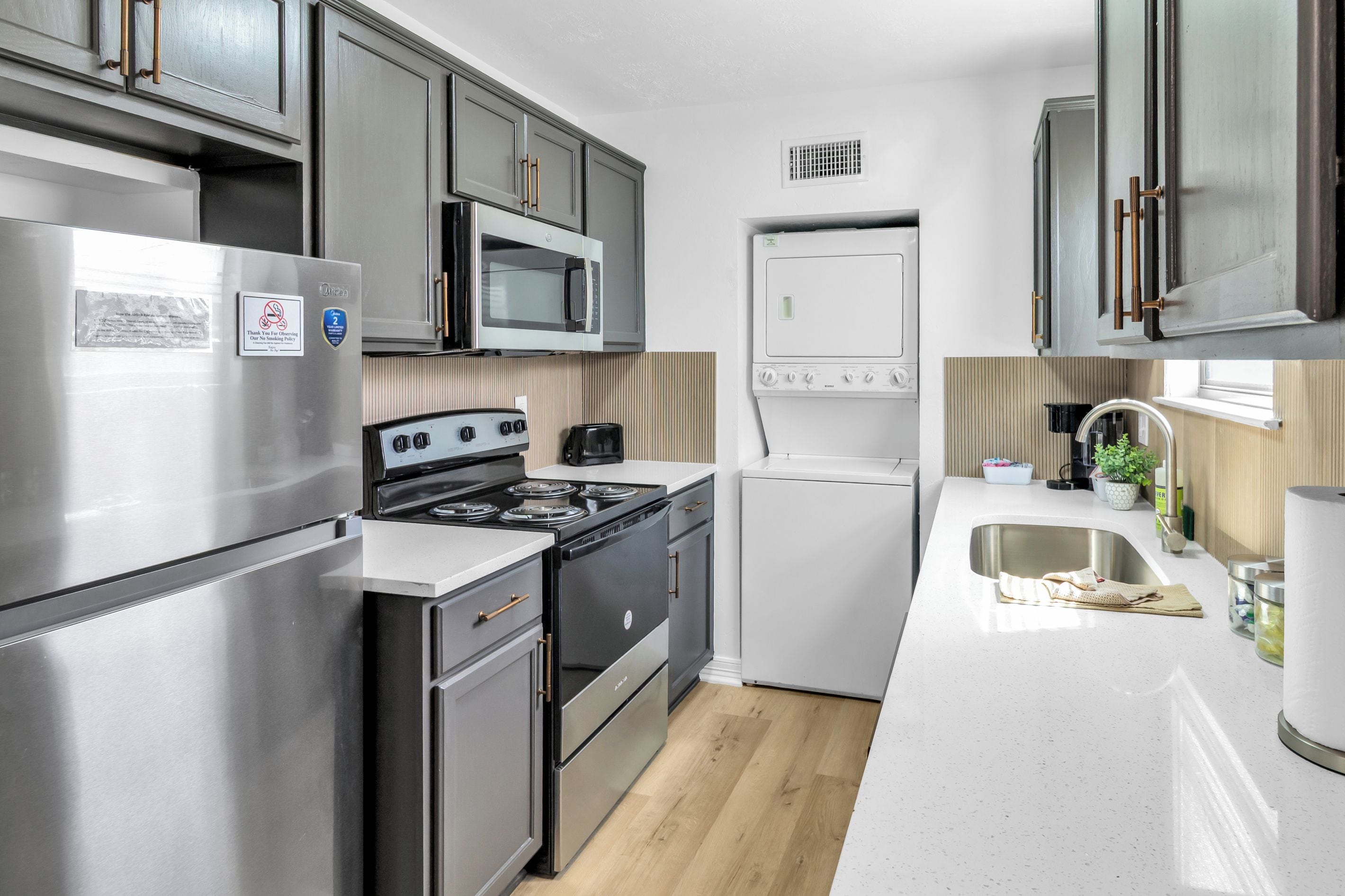 A compact kitchen with a refrigerator, stove, microwave, oven, and sink.