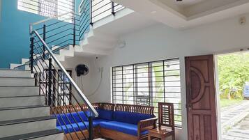 A modern interior with a staircase, a blue sofa, and a red carpet.