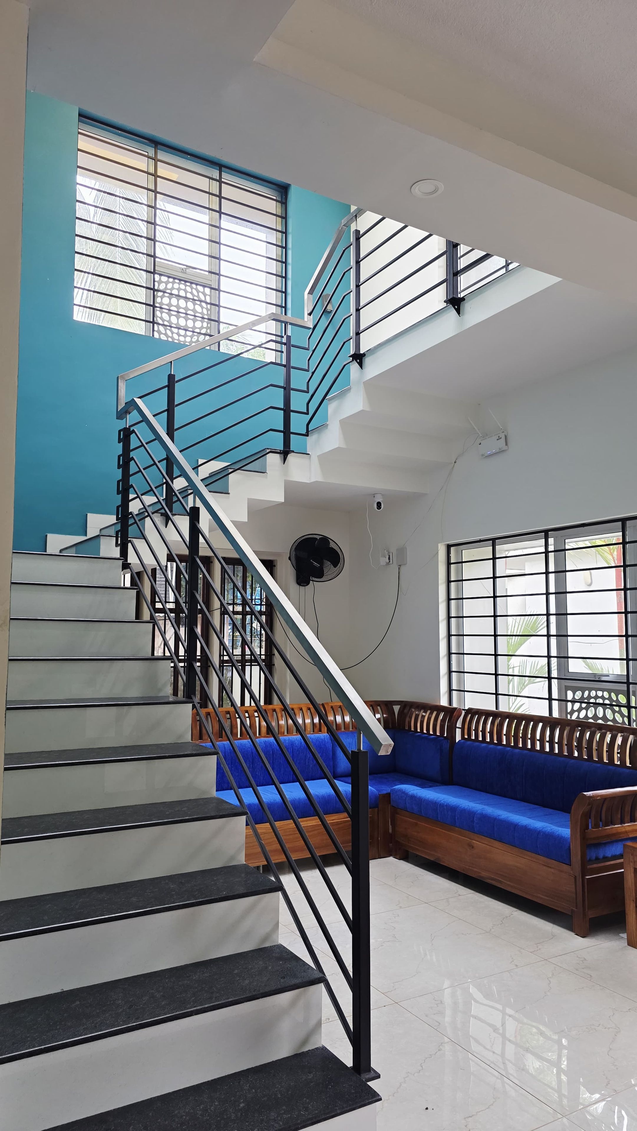 A staircase with a blue railing, a blue sofa, and a ceiling fan.