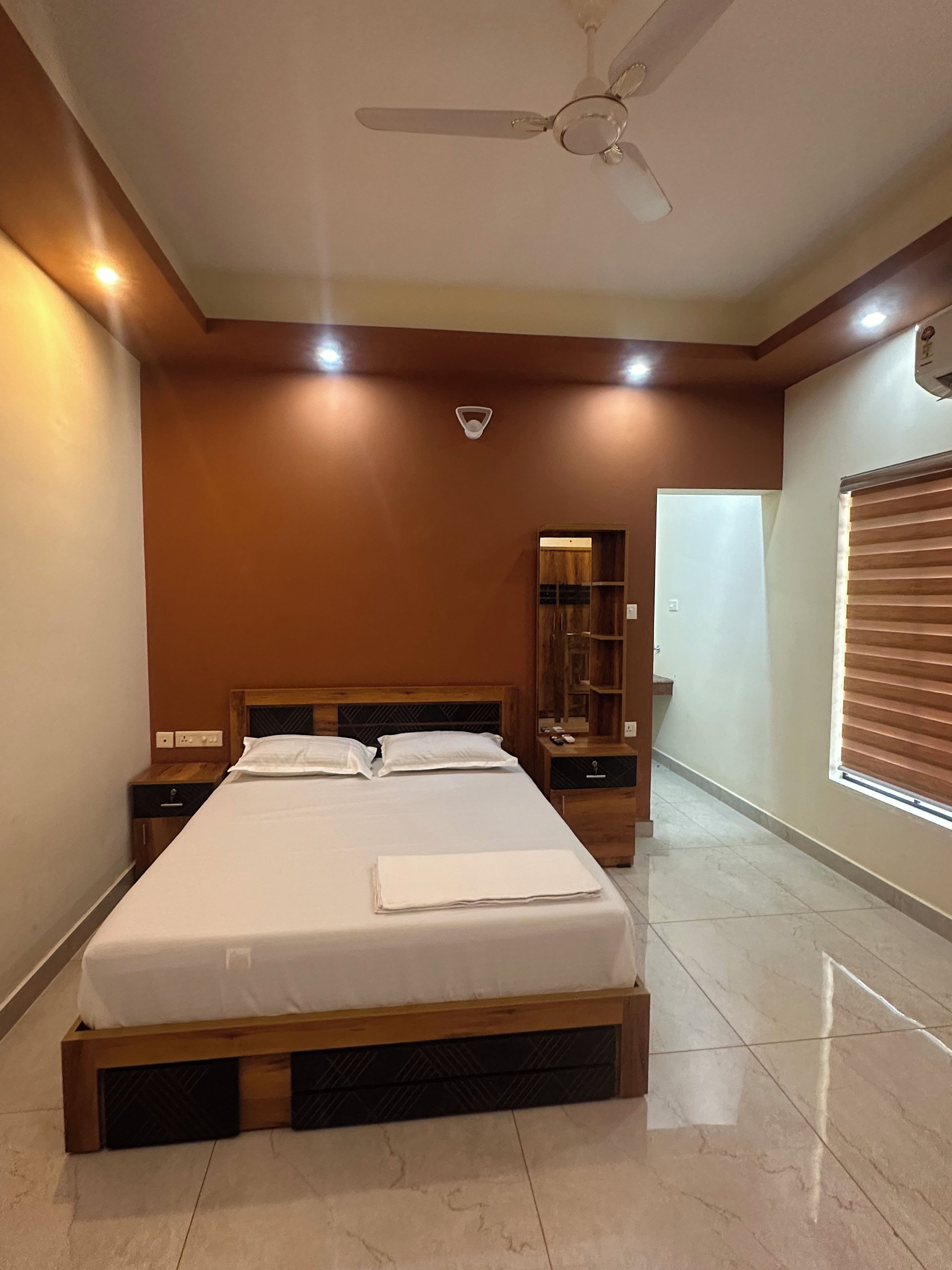 A bedroom with a bed, nightstands, a ceiling fan, and a window with blinds.