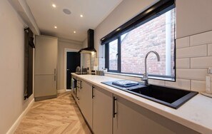 A modern kitchen with a large window, a black sink, and a herringbone wood floor. - Cosy 2 bed tce - walk to city centre (Chester)