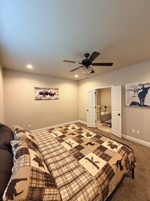 A bedroom with a large bed, a ceiling fan, and two doors leading to other rooms.