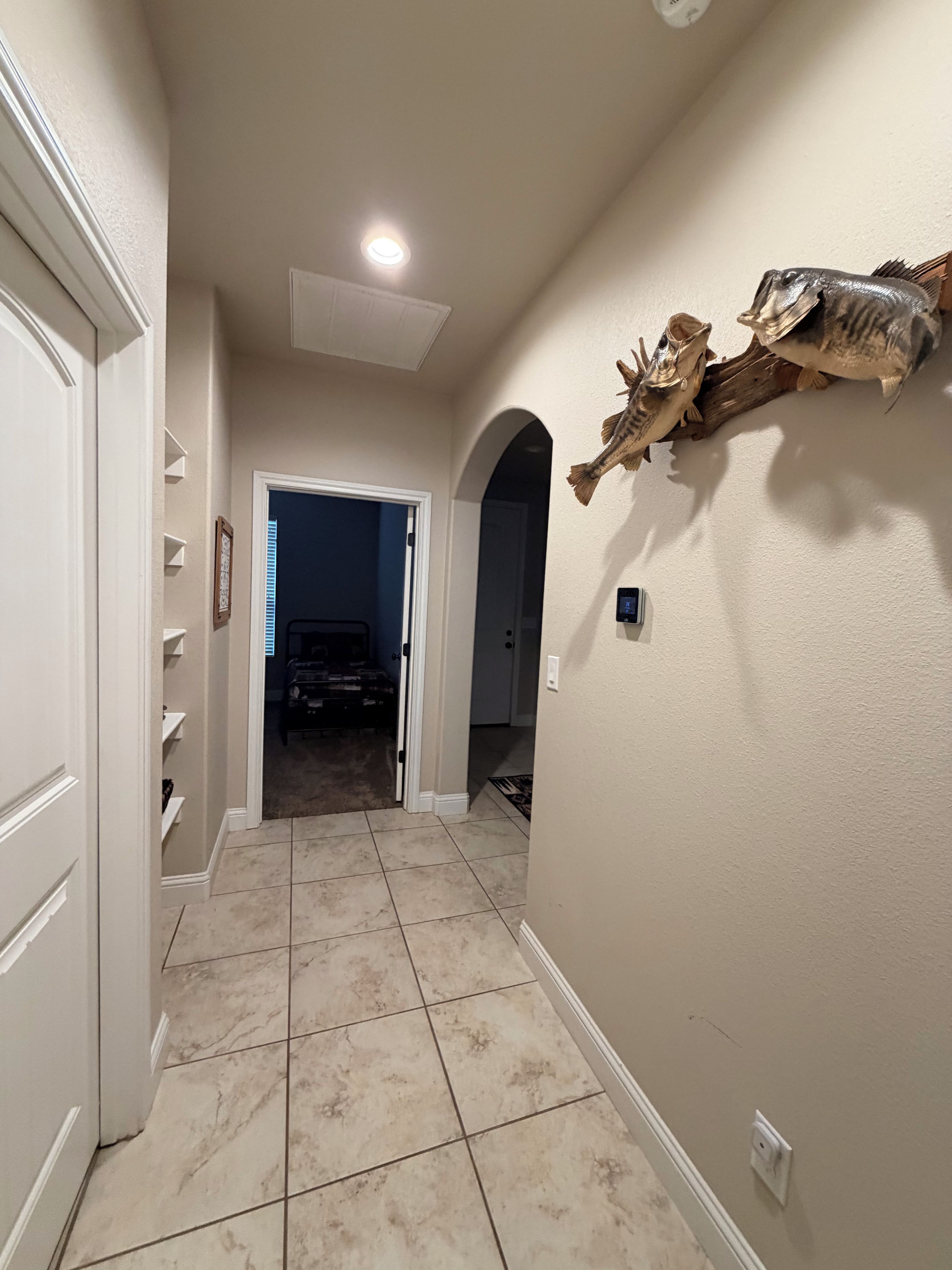 Un couloir doté d’un sol carrelé, d’une porte blanche et d’un squelette de poisson décoratif fixé au mur.