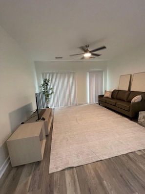 A spacious living room with a large rug, a brown sofa, a ceiling fan, and a potted plant. - Updated 2Bedroom with a pool and hot tub (Columbus)