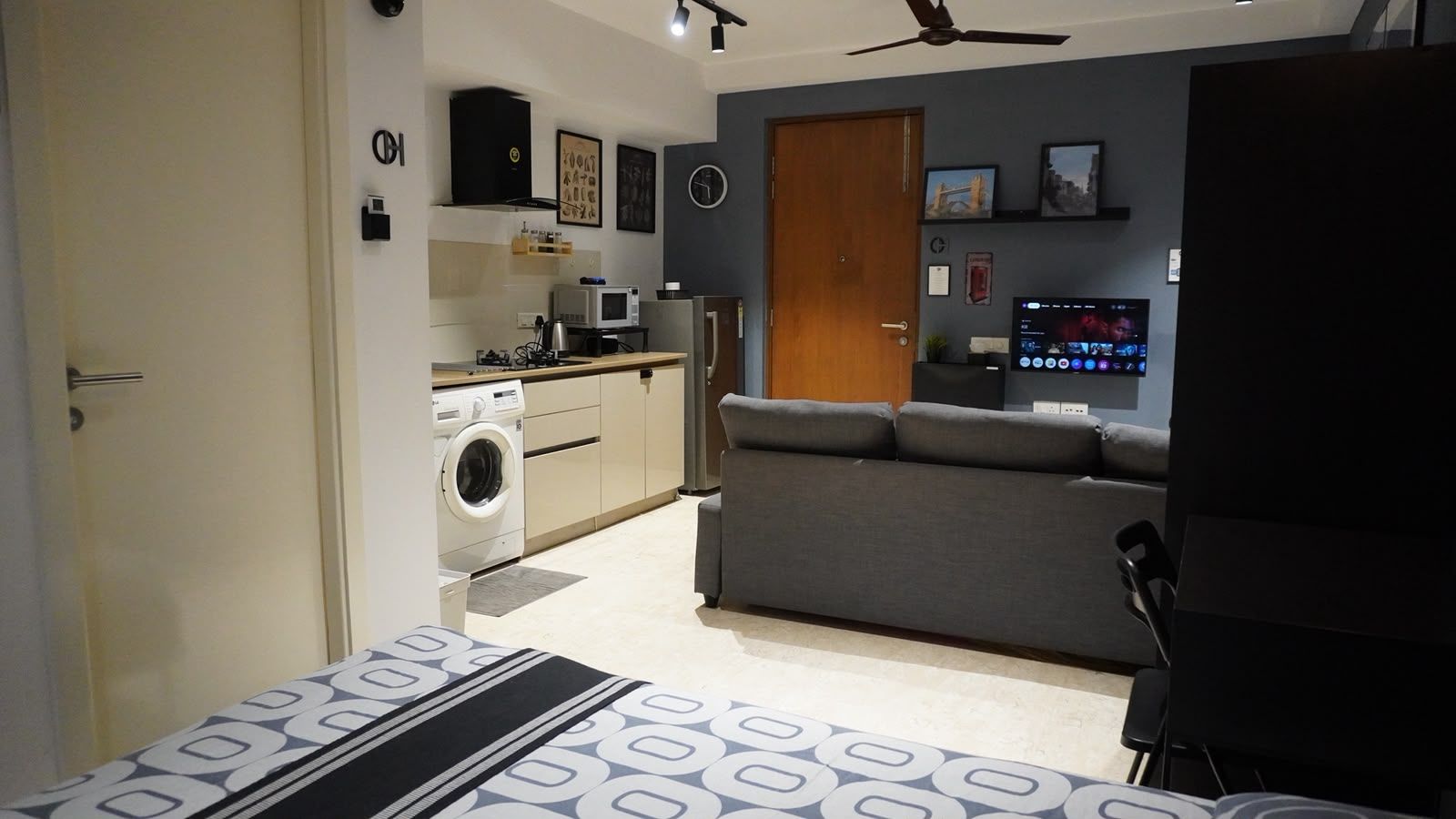 A compact living space with a kitchenette, a sofa, a washing machine, and a television.