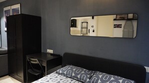 Een kamer met een bed, een bureau en een kledingkast.
