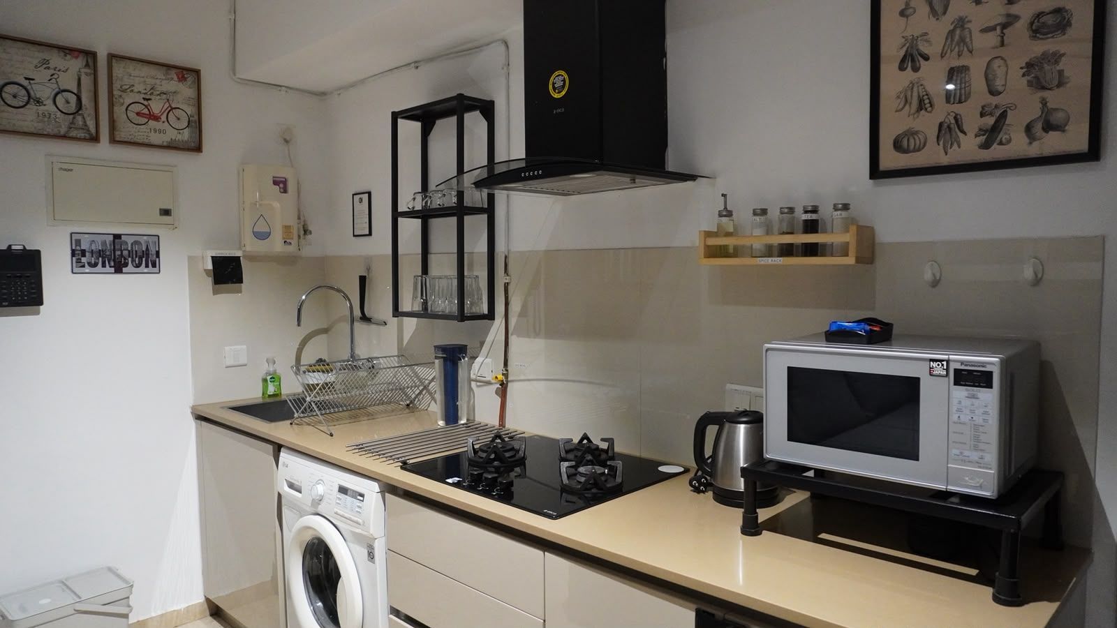 A compact kitchen with a washing machine, a microwave, and a kettle.