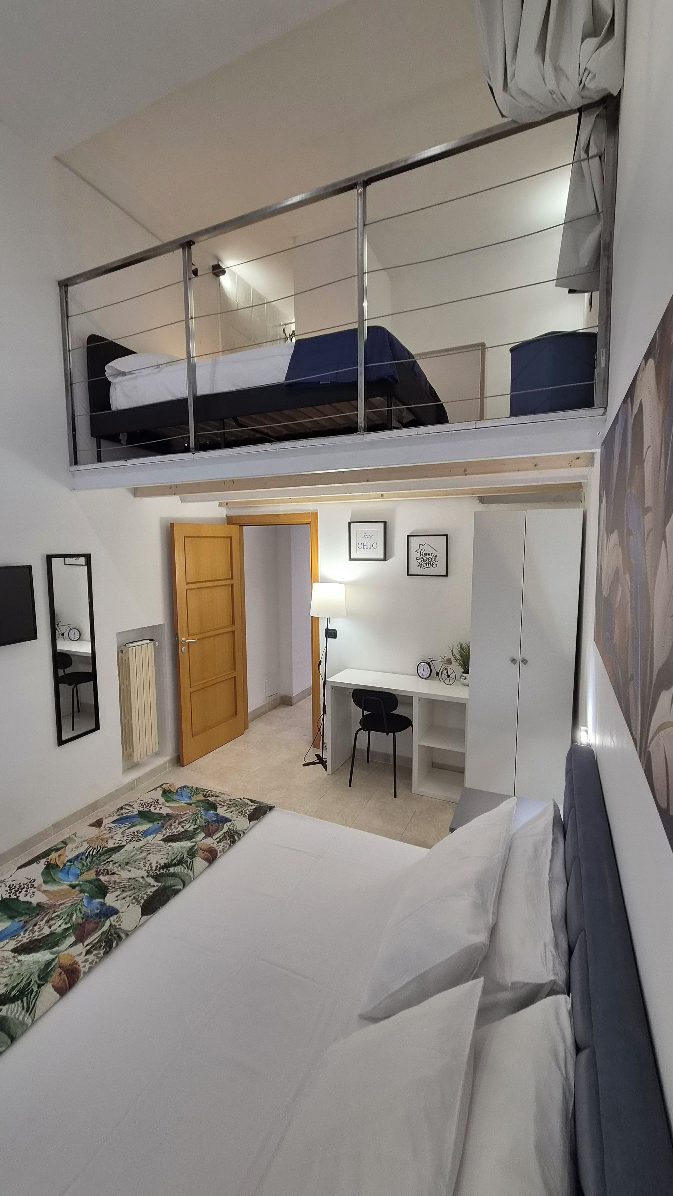 Habitación tipo dormitorio con literas, un escritorio, una silla, un radiador y una puerta.