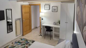 Habitación tipo dormitorio con literas, un escritorio, una silla, un radiador y una puerta.
