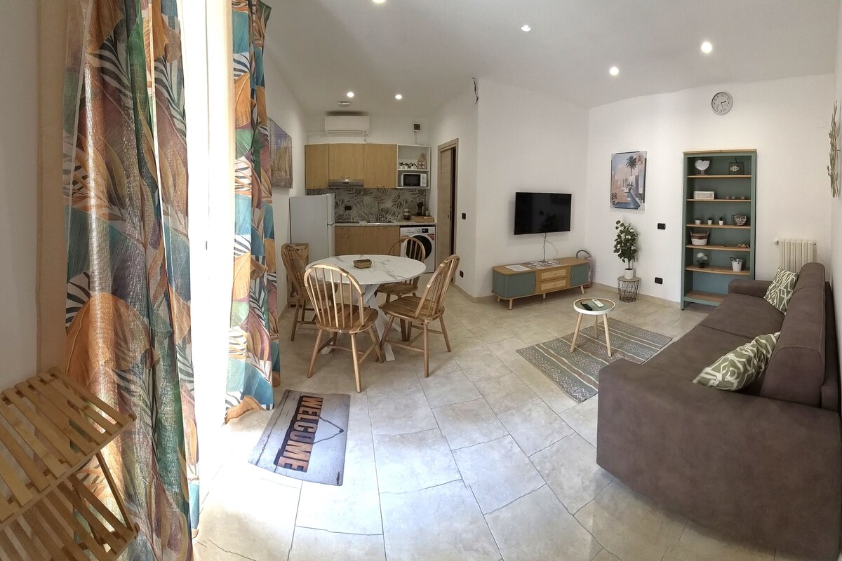 A living room with a sofa, a TV, and a dining area with chairs and a table.