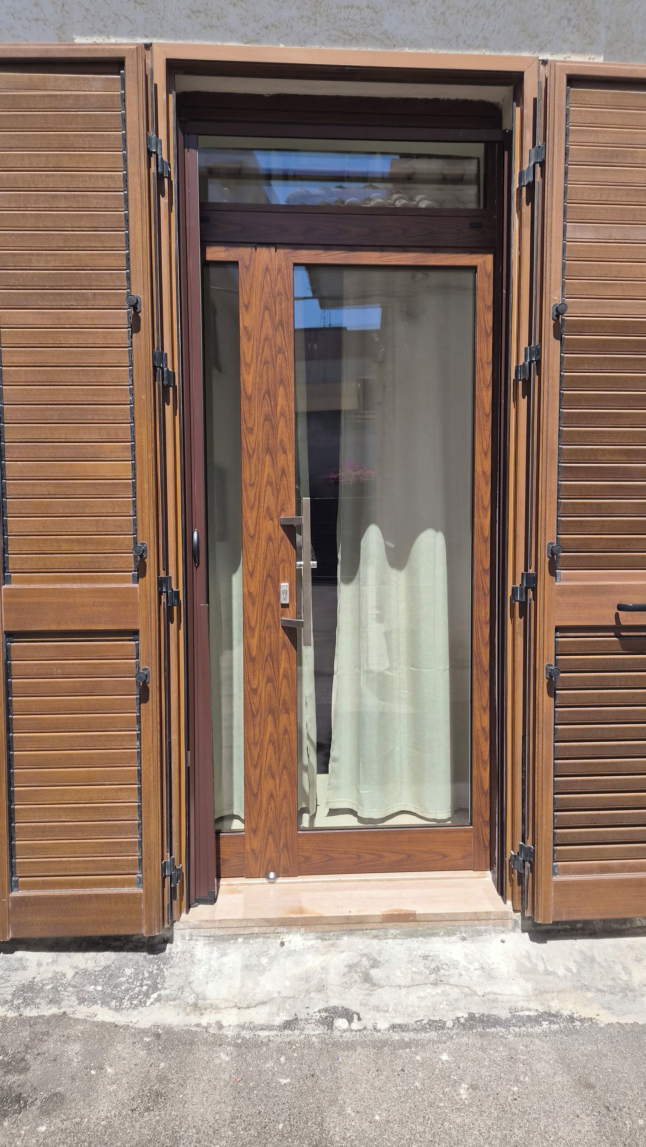Uma porta de madeira com um painel de vidro e cortina.