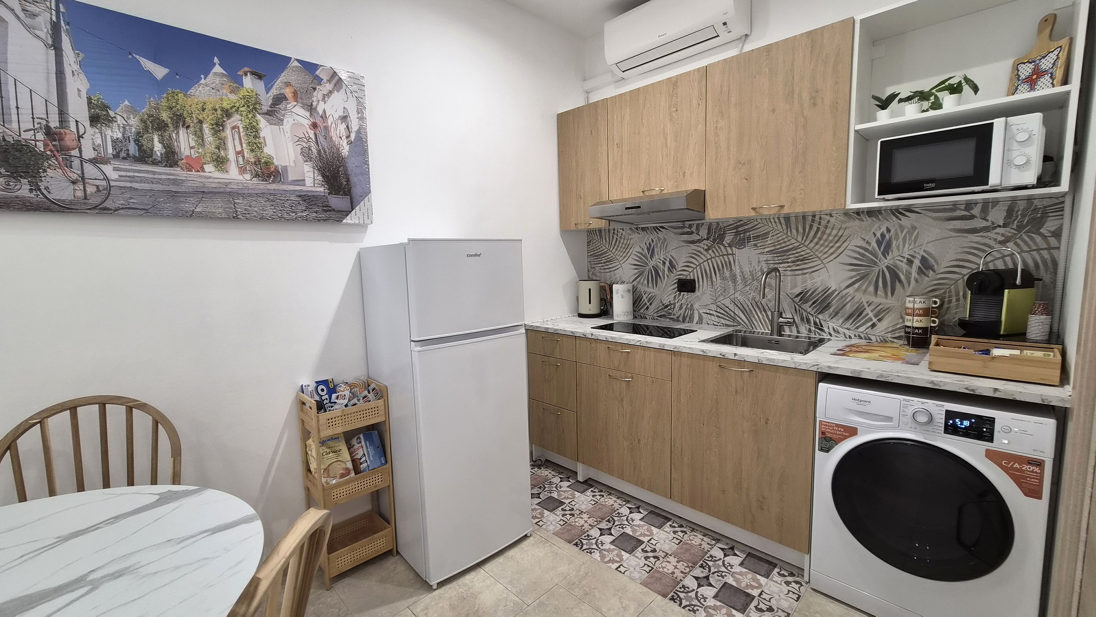 A compact kitchen with a refrigerator, microwave, sink, and washing machine.