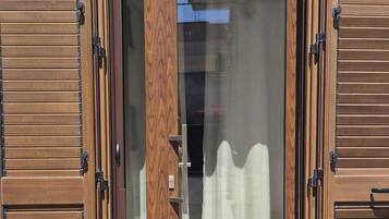 Ein moderner Eingangsbereich mit Glastür und Holzklappläden.