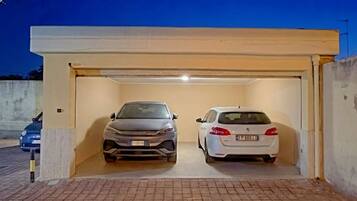 Área de estacionamento coberta com dois carros estacionados.