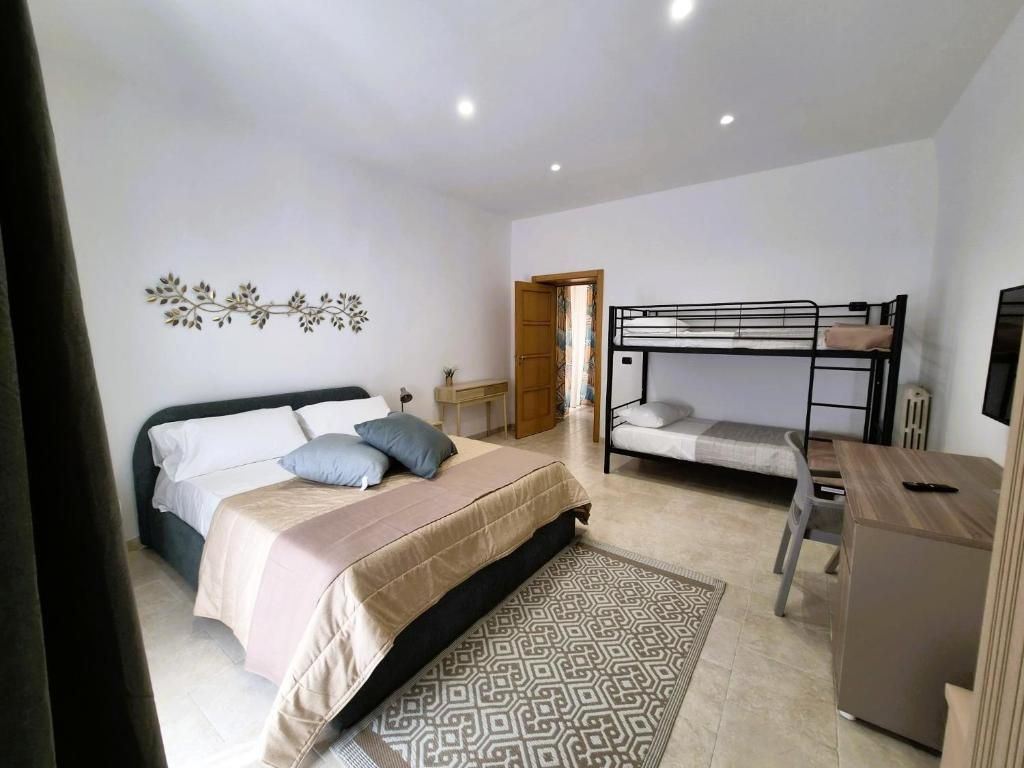 Un dormitorio con una cama individual, una litera, un escritorio y una silla.