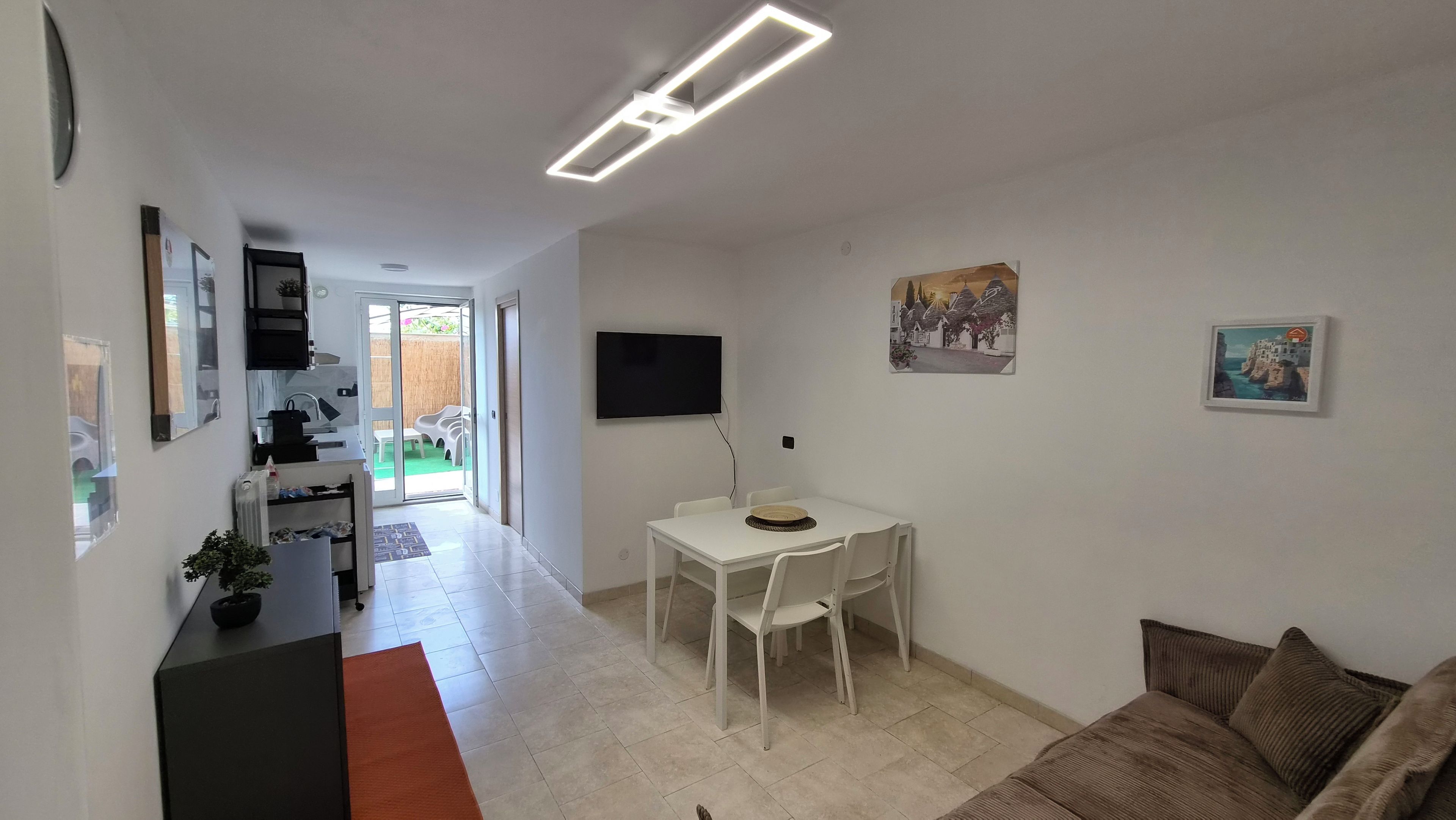 A modern living room with a dining area, a flat-screen TV, and artwork on the walls.