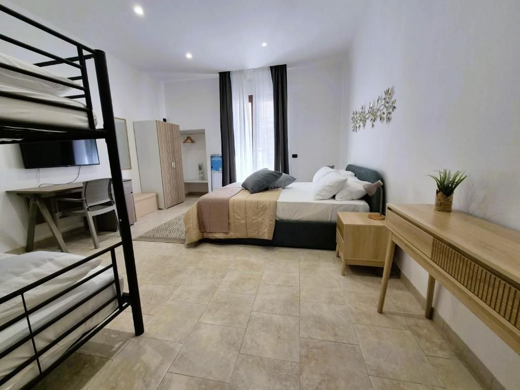 A bedroom with a bunk bed, a desk, a bedside table, and a television.