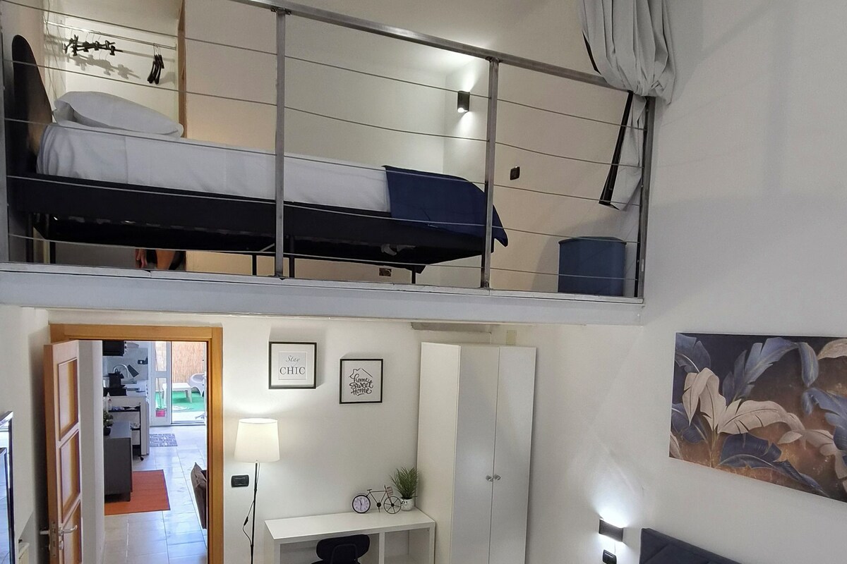 Un dormitorio con literas, un escritorio, una silla, un armario y una cama con colcha estampada.