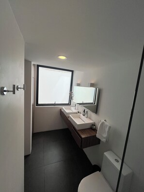 Un baño moderno con lavamanos doble, inodoro y ventana que proporciona luz natural.