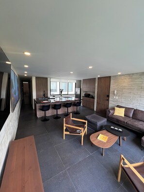 A modern living area with a sofa, coffee table, and a dining area with bar stools. - Superb 2-bedroom apartment in welcoming Colonia del Valle neighborhood (Ciudad de México)