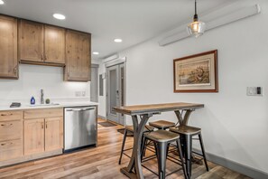 A modern kitchen with wooden cabinets, a stainless steel dishwasher, and a bar area with stools. - Tranquil Riverfront Property Close to the Resort! Pet Friendly! (Steamboat Springs)