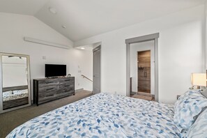 A bedroom with a bed, dresser, television, and a door leading to a bathroom. - Tranquil Riverfront Property Close to the Resort! Pet Friendly! (Steamboat Springs)