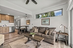 A modern living room with a sofa, coffee table, and a dining area with chairs and a table. - Tranquil Riverfront Property Close to the Resort! Pet Friendly! (Steamboat Springs)